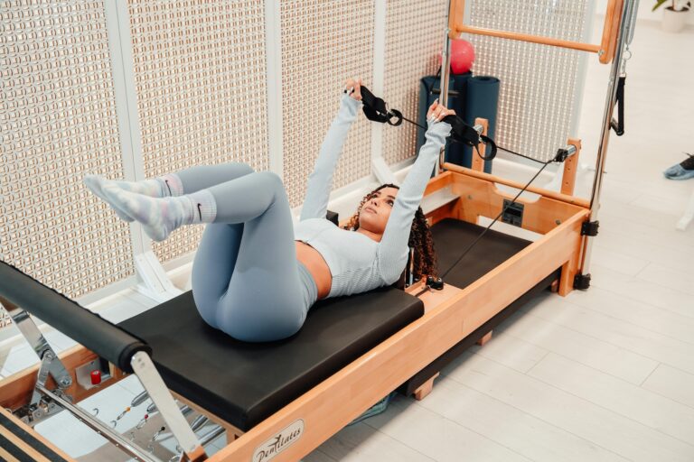 Woman Laying and Exercising on a Pilates Reformer Machine