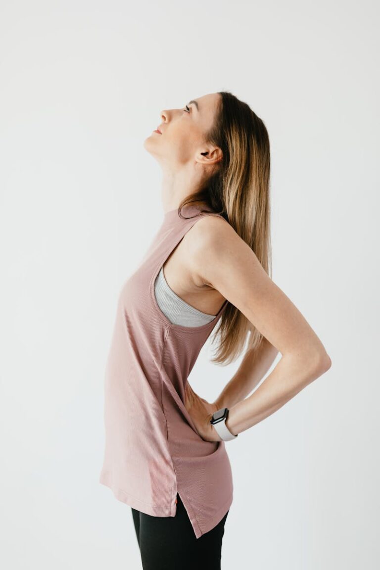 A young woman in activewear performs a yoga pose against a white studio background, promoting wellness.