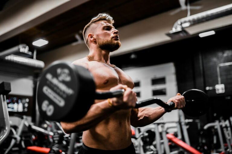 topless man in black shorts carrying black dumbbell weight workout